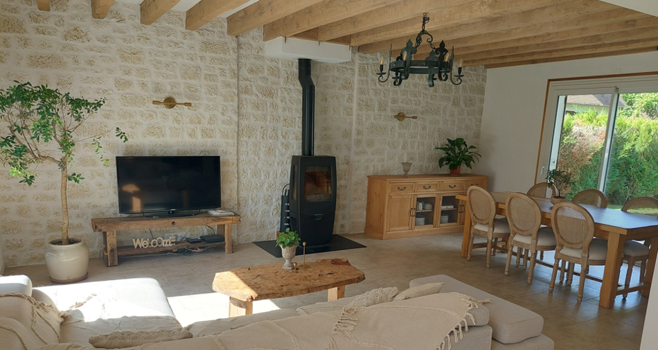 Valoriser Murs Intérieurs Maison avec salon en pierre reconstituée, TV murale et poêle décoratif.