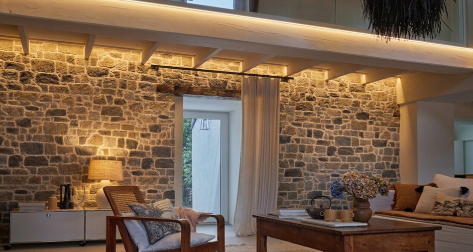 Éclairage mur pierre reconstituée avec lumière descendante mettant en valeur la texture et le relief d’un mur intérieur